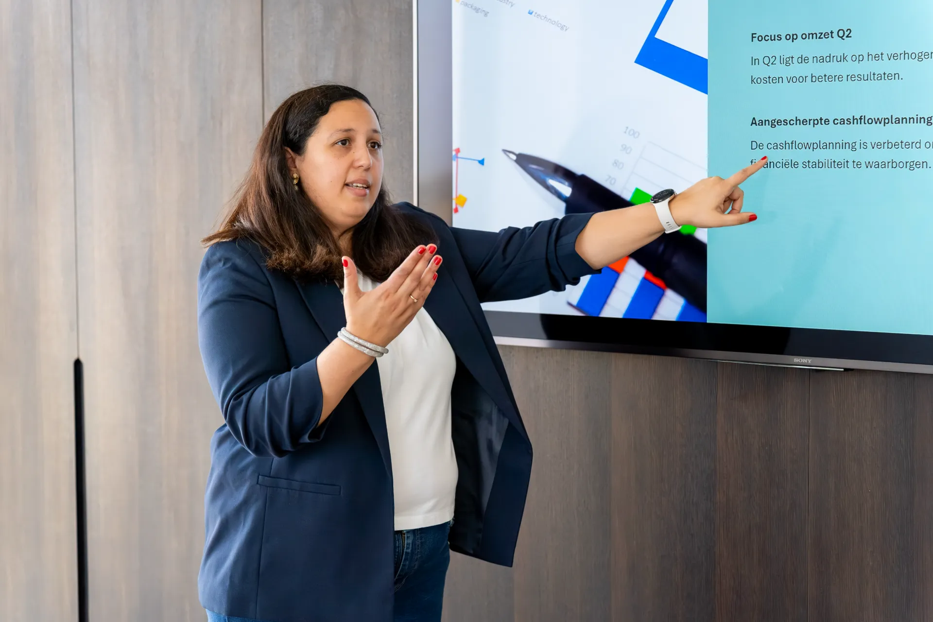 Een financieel adviseur wijst naar een scherm met cashflowplanning en kwartaalresultaten tijdens een presentatie.
